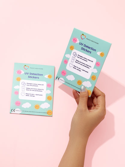 Two UV Detection Stickers cards by Peachy Healthcare held against a pink background